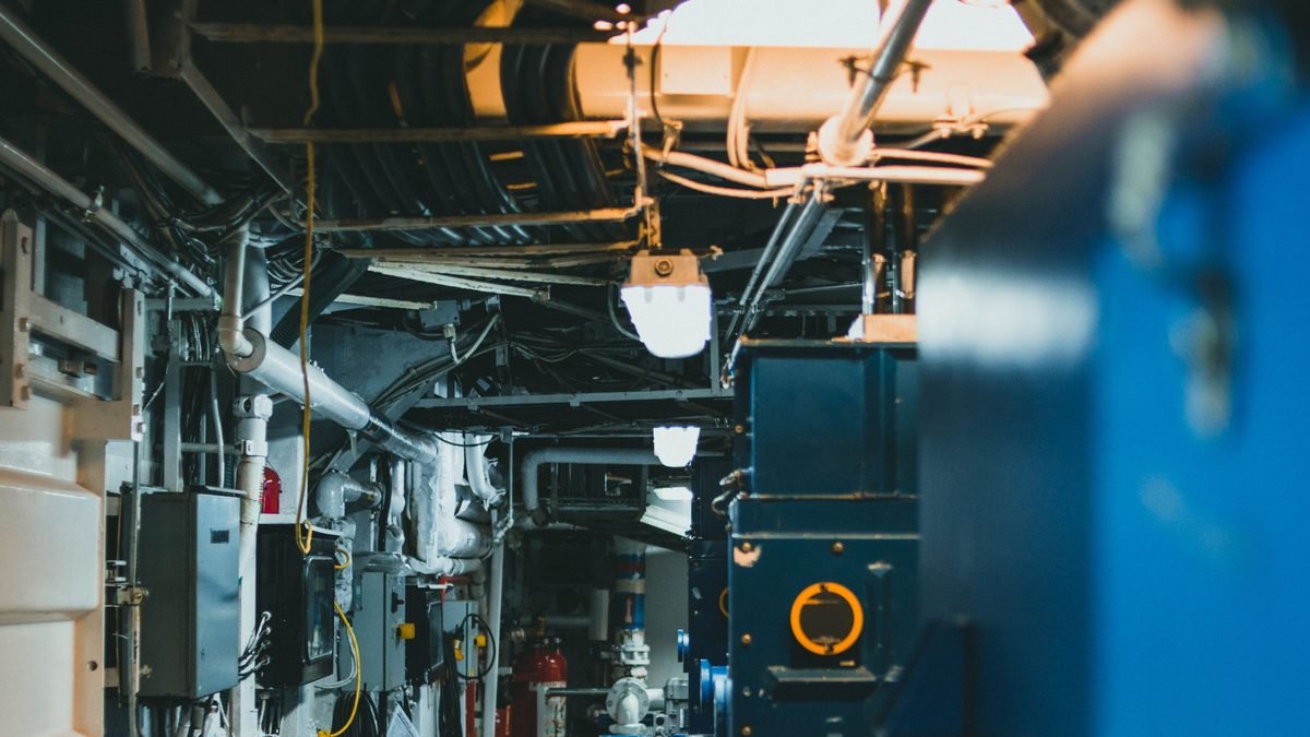 Sala de caldeiras industrial com tubulações, válvulas e painéis de comando
