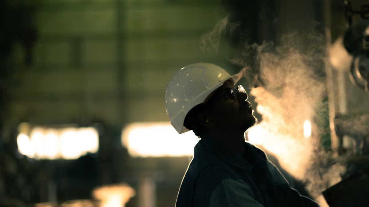 Técnico industrial em ambiente com vapor, usando capacete de segurança